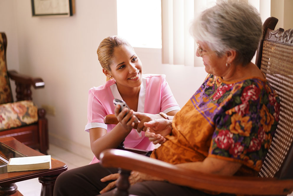 younger person assisting elder woman on phone